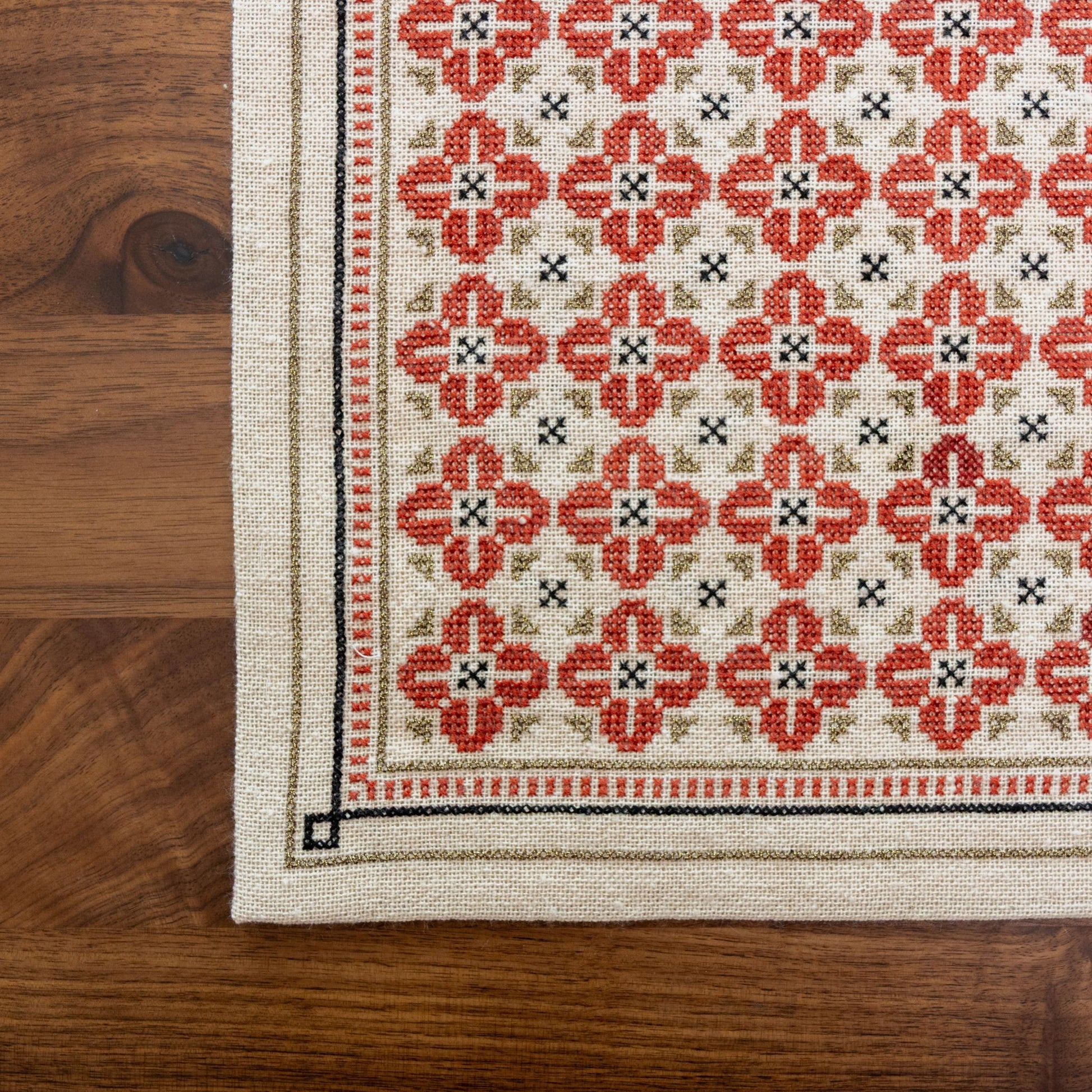 folk embroidery with repeating flower design in red, black and metallic thread