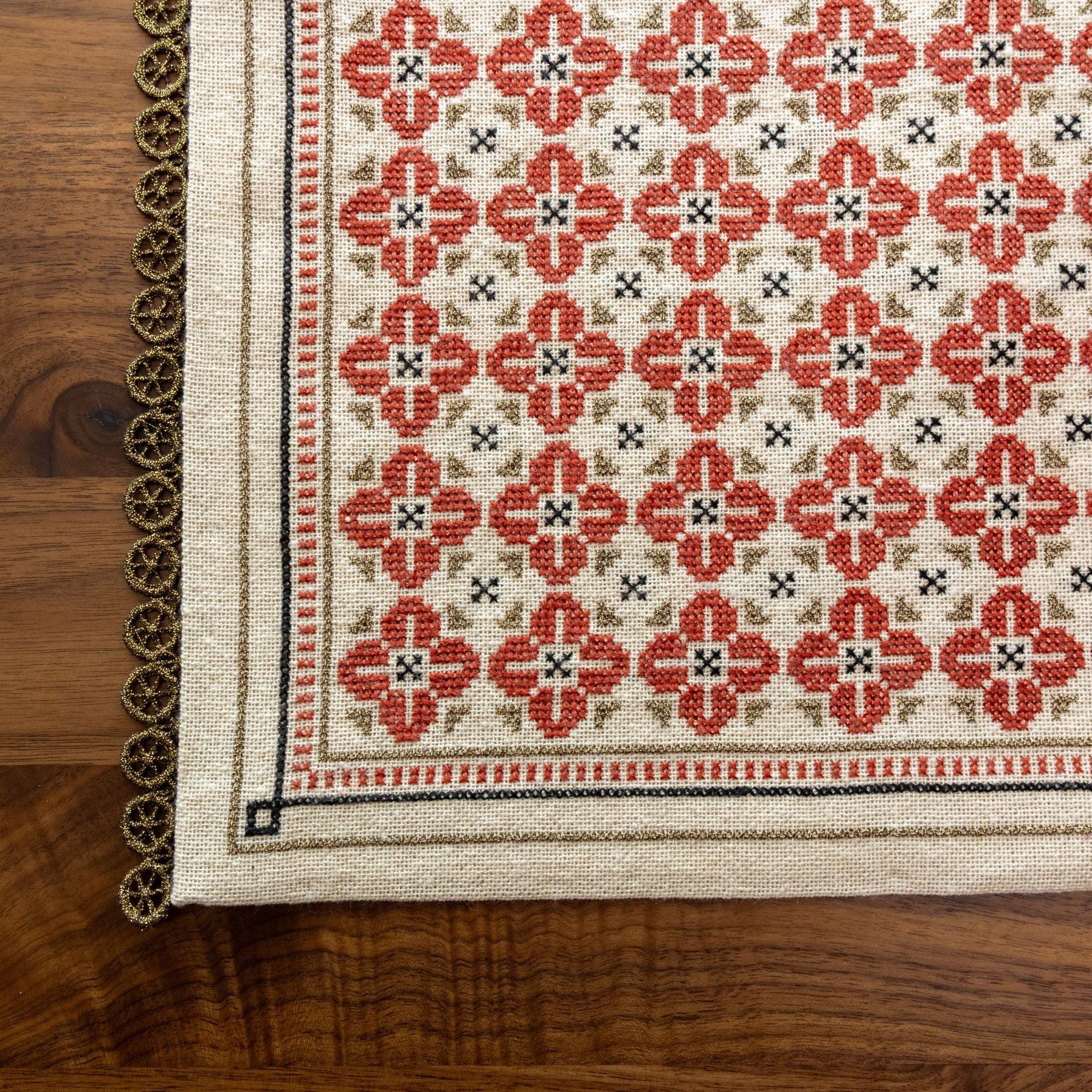 folk embroidery with repeating flower design in red, black and metallic thread