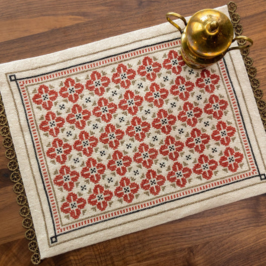 folk embroidery with repeating flower design in red, black and metallic thread