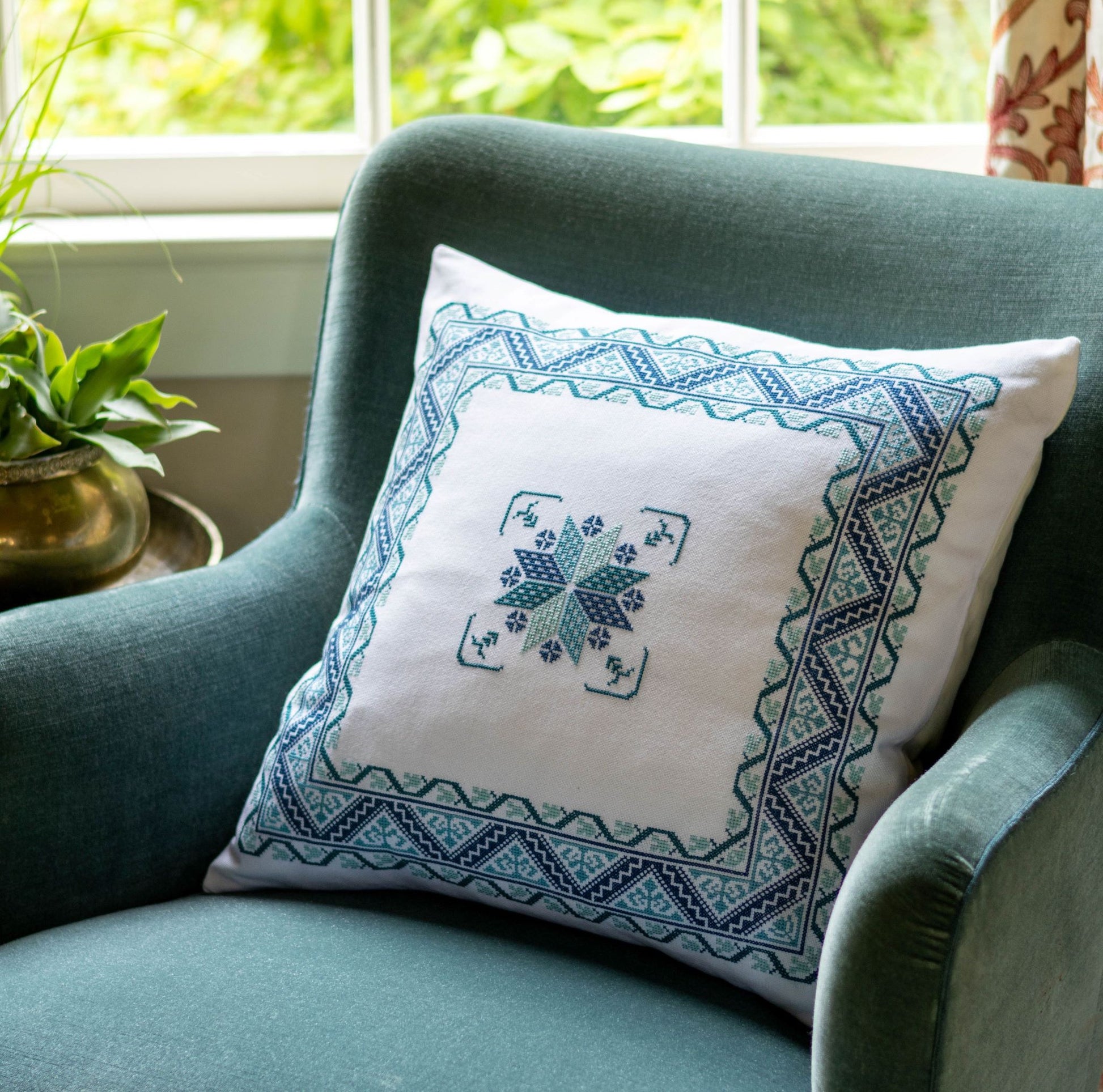 folk embroidery cushion with blue border design in blue chair