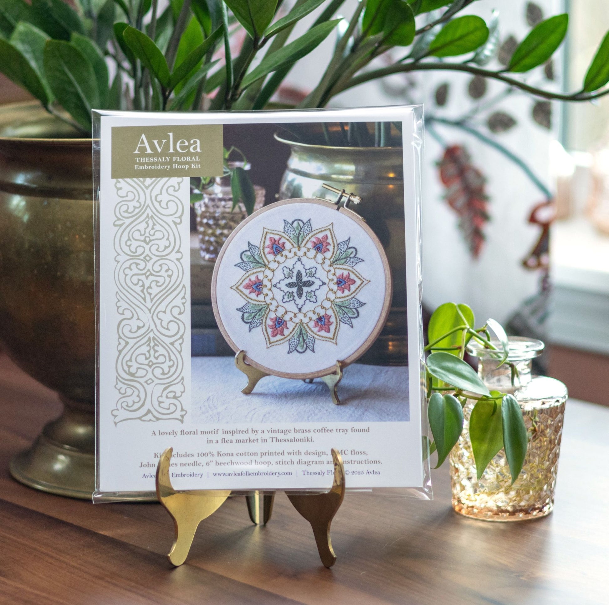 Avlea embroidery kit packaging with a floral design on a wooden surface with plants in the background