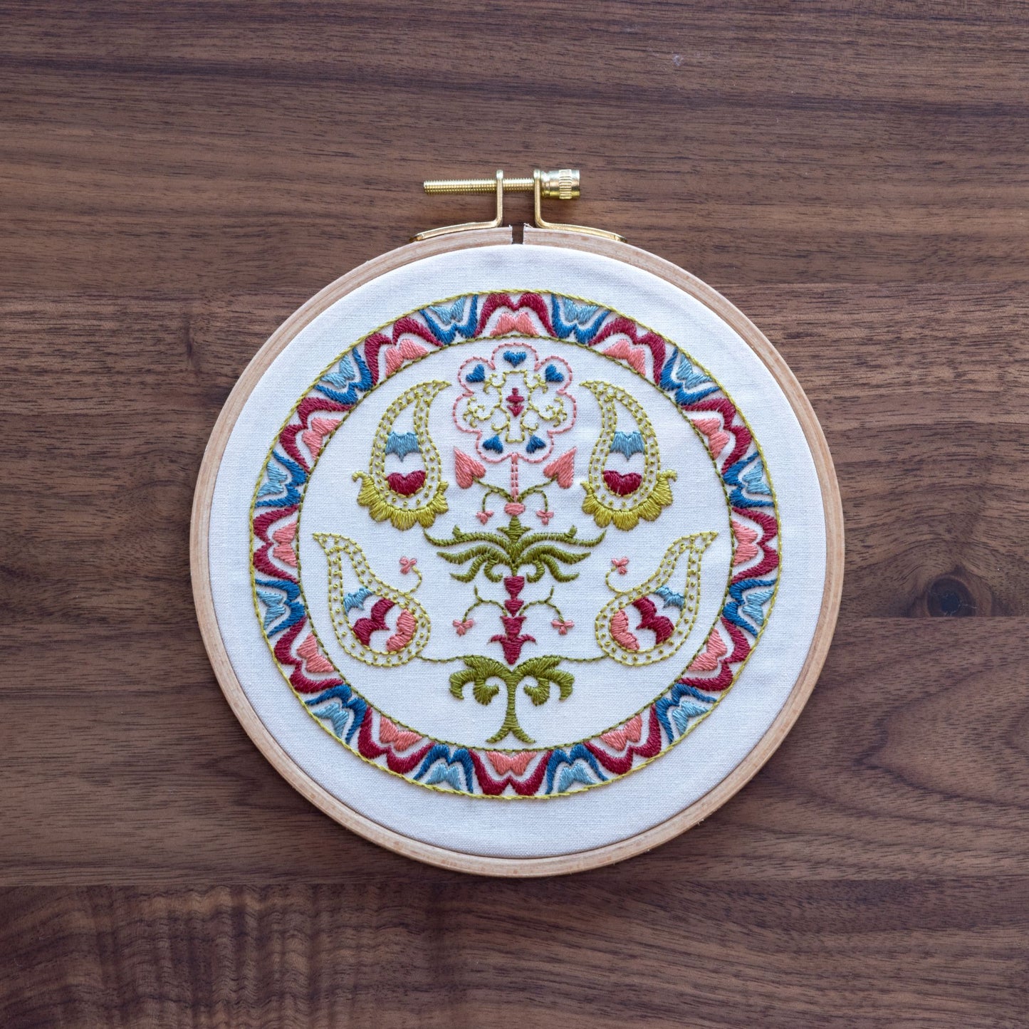 Embroidery hoop with colorful floral design on a wooden surface
