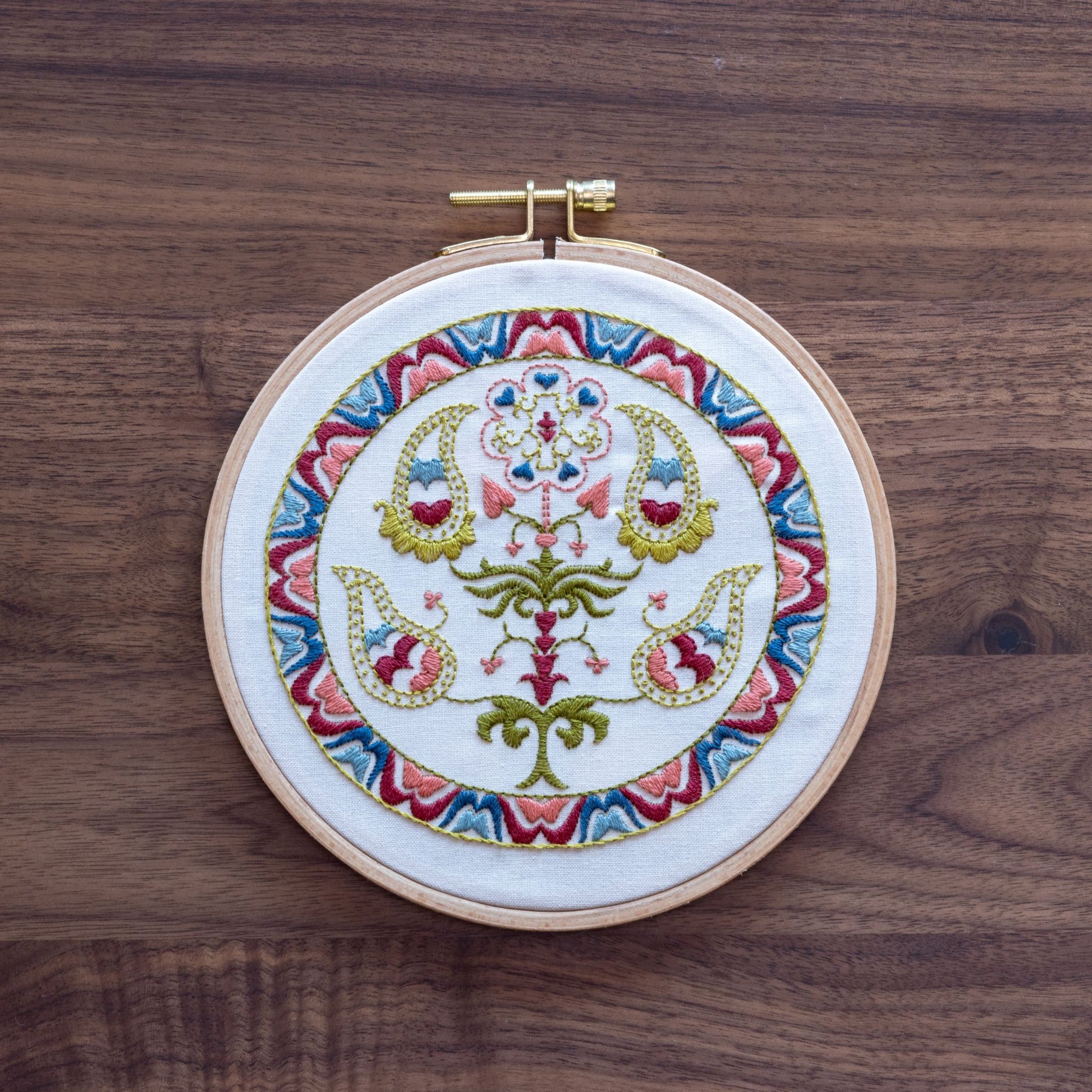 Embroidery hoop with colorful floral design on a wooden surface