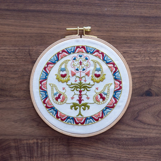 Embroidery hoop with colorful floral design on a wooden surface
