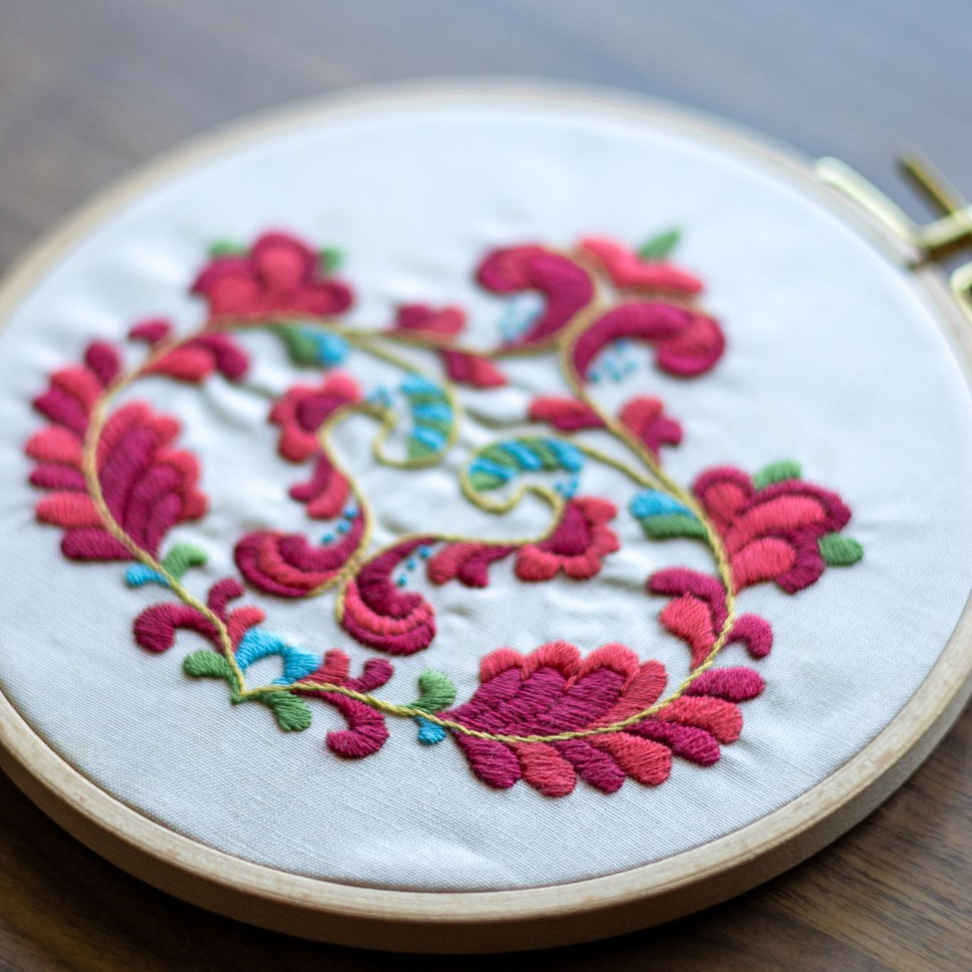 Embroidery hoop with colorful floral pattern on a wooden surface