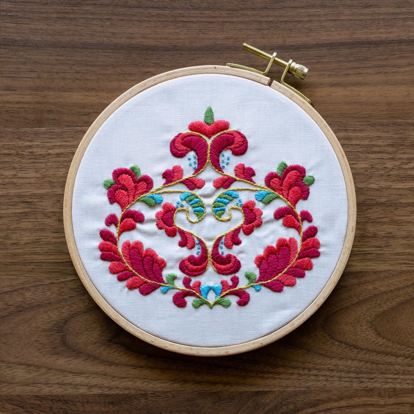 Embroidery hoop with norwegian floral design on a wooden surface