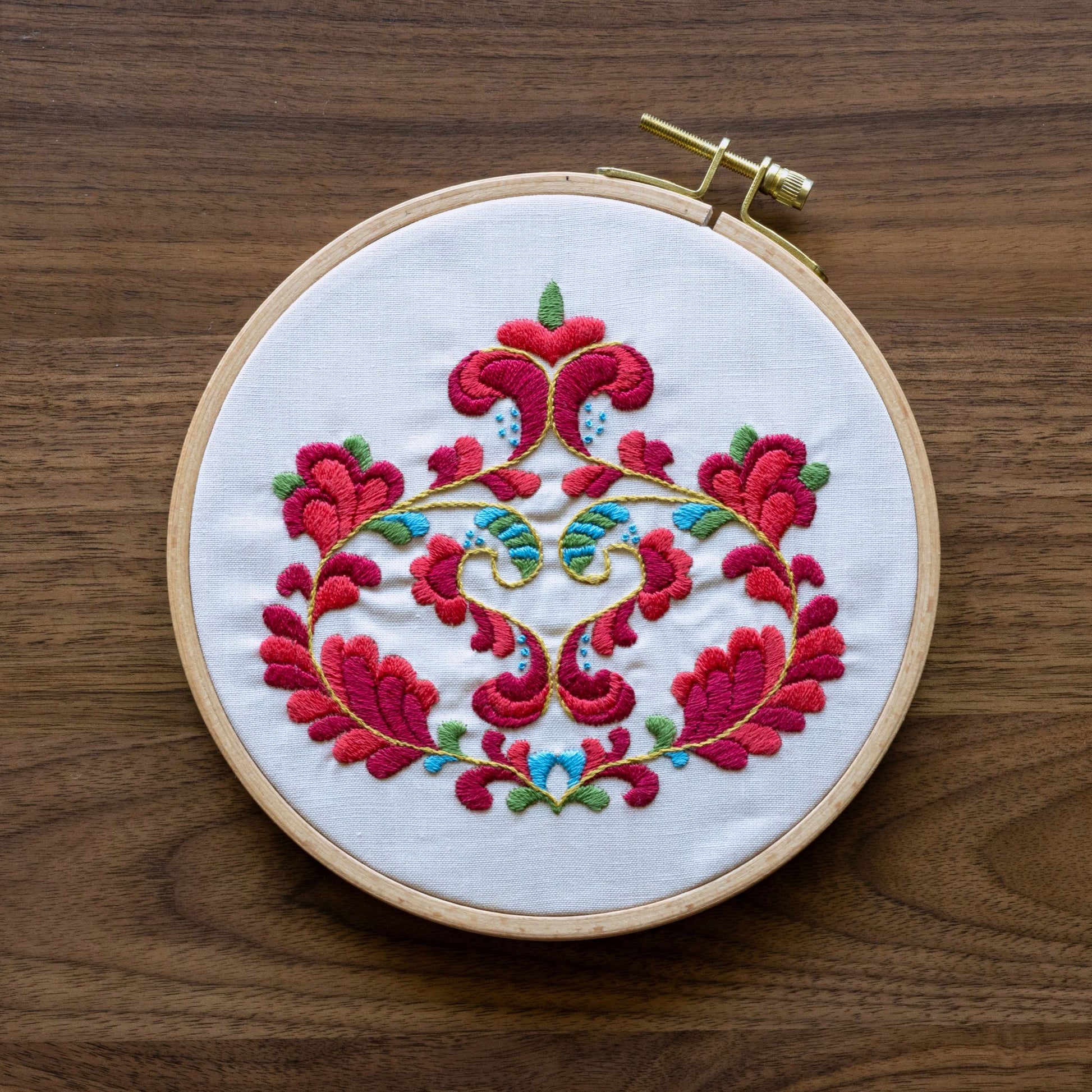 Embroidery hoop with norwegian floral design on a wooden surface