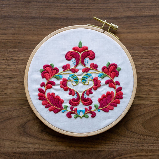 Embroidery hoop with norwegian floral design on a wooden surface